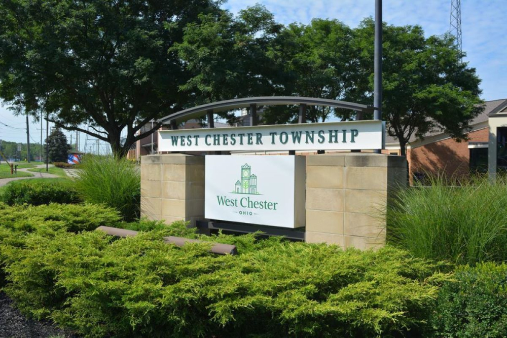 West Chester Ohio - Elegant Outdoor Lighting Design West Chester Township, Ohio entrance sign set on stone pillars with surrounding greenery and trees.