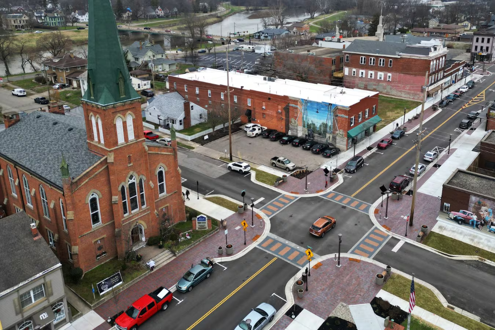 Franklin-Ohio-Roofers - Elegant Outdoor Lighting Design Aerial view of a red-brick church on a corner, with a four-way intersection and striped crosswalks in a small town.